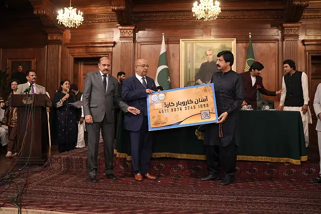 The Governor of Punjab holds up a large Asaan Karobar Card on stage