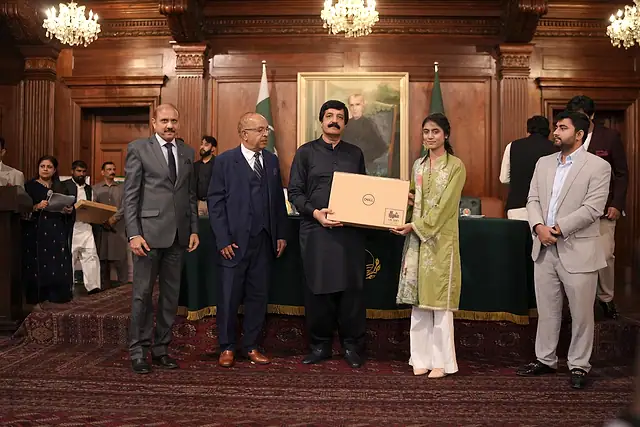 The Governor of Punjab hands a laptop box to a student on stage