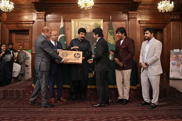 The Governor of Punjab hands a laptop box to a young man