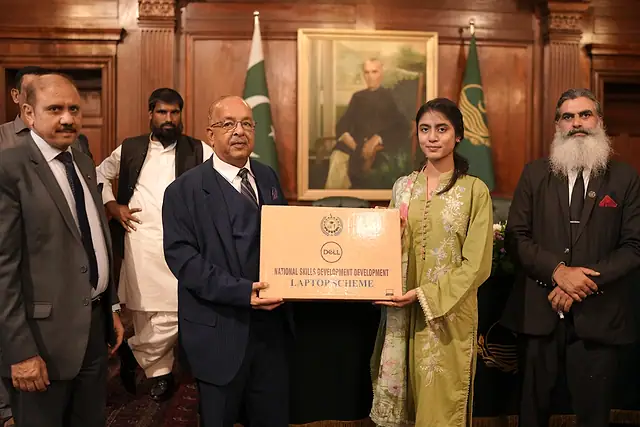 Major General Zawar Hussain Shah (Retd) presents a laptop box to a young woman