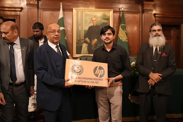 Major General Zawar Hussain Shah (Retd) presents a laptop box to a young man
