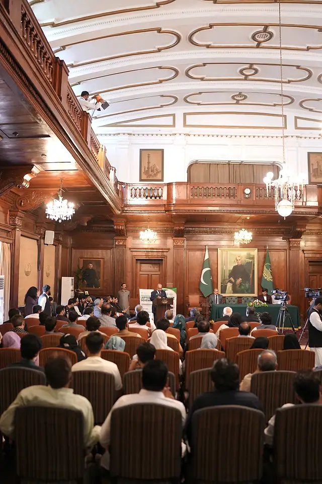 A packed, wood-panelled ceremony hall seen from the back