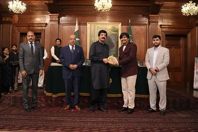 The Governor of Punjab presents a shield to a guest in a maroon coat